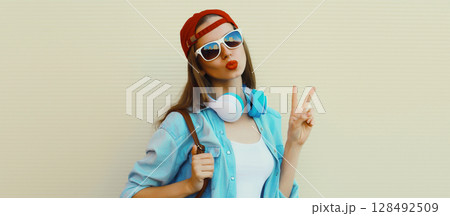 Stylish modern young woman listening to music with headphones, cool girl in baseball cap posing Stylish modern young woman listening to music with headphones, cool girl in baseball cap posing 128492509