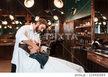 Sitting on the chair. Man is visiting modern barber shop. Modern style 128492664