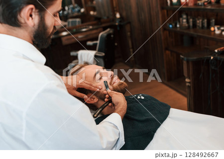 Sitting on the chair. Man is visiting modern barber shop. Modern style 128492667