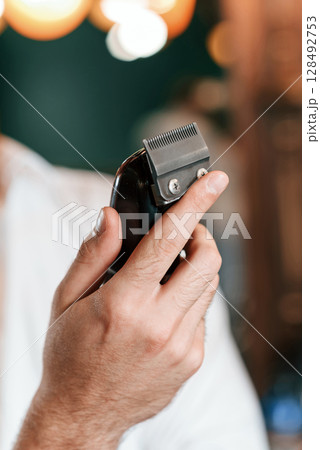 Close up view of barber hand that is holding hair clipper 128492753