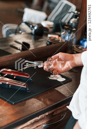 Close up view of barber hand that is holding scissors 128492761