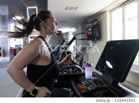 Real woman with a normal body working out on treadmill in gym. Realistic fitness and healthy weight loss motivation Real woman with a normal body working out on treadmill in gym. Realistic fitness and healthy weight loss motivation 128492891