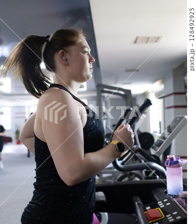 Real woman with a normal body working out on treadmill in gym. Realistic fitness and healthy weight loss motivation 128492925