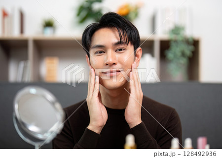 Self-Care. Man smiling after applying skincare products at home. 128492936