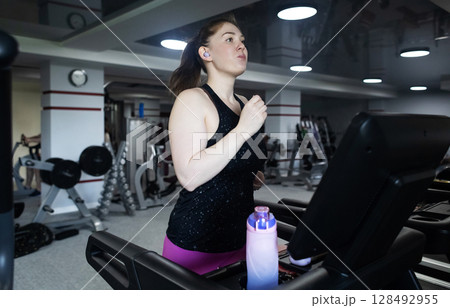 Real woman with a normal body working out on treadmill in gym. Realistic fitness and healthy weight loss motivation Real woman with a normal body working out on treadmill in gym. Realistic fitness and healthy weight loss motivation 128492955