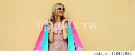 Fashion, clothing. Stylish beautiful happy woman with colorful shopping bags in summer dress 128492989