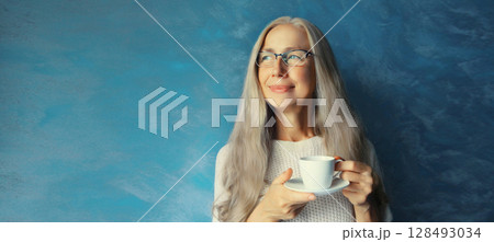 Happy smiling woman enjoying hot tasty cup of coffee or tea standing in morning at home Happy smiling woman enjoying hot tasty cup of coffee or tea standing in morning at home 128493034