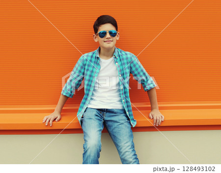 Modern teenage kid boy in casual clothes with glasses standing on city street 128493102