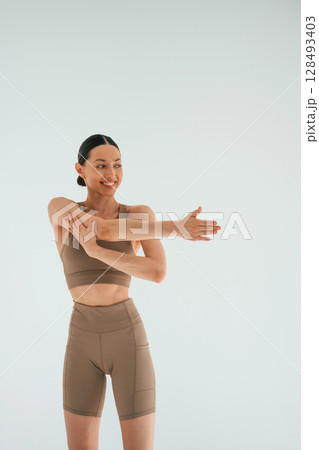 Smiling, feeling good. Young woman with slim body type is in fitness clothes in the studio 128493403