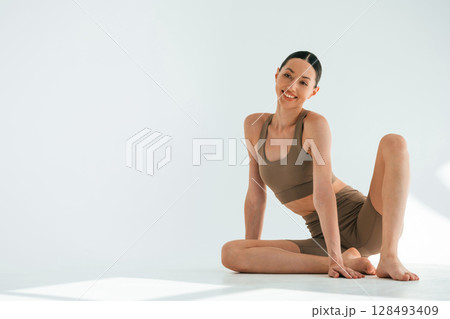 Smiling, feeling good. Young woman with slim body type is in fitness clothes in the studio 128493409