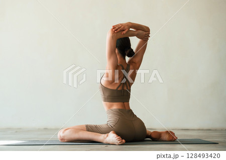 In grey fitness clothes. Young woman with slim body type is in the studio 128493420