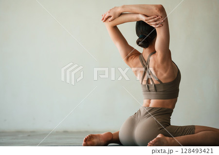 In grey fitness clothes. Young woman with slim body type is in the studio 128493421