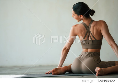 In grey fitness clothes. Young woman with slim body type is in the studio 128493422