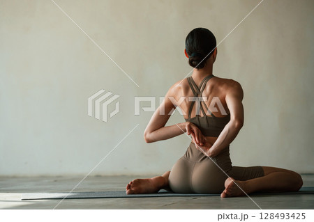 Yoga session. Young woman with slim body type is in fitness clothes in the studio 128493425