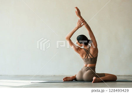 Yoga session. Young woman with slim body type is in fitness clothes in the studio 128493429
