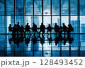 A group of business people sitting at a conference table in a modern office with large windows. 128493452