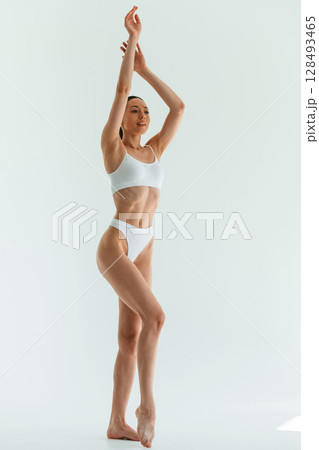 With hands up. Young woman with slim body type is in fitness clothes in the studio With hands up. Young woman with slim body type is in fitness clothes in the studio 128493465
