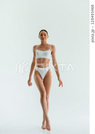 Against white background. Young woman with slim body type is in fitness clothes in the studio 128493466