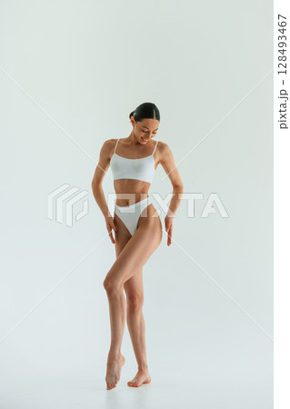 Against white background. Young woman with slim body type is in fitness clothes in the studio 128493467