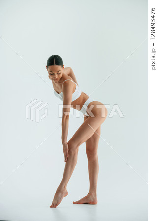 In the studio with white background. Young woman with slim body type is in fitness clothes 128493476