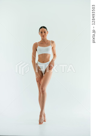 In the studio with white background. Young woman with slim body type is in fitness clothes 128493503