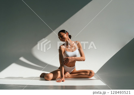 Sitting, enjoying the break time. Young woman with slim body type is in fitness clothes in the studio Sitting, enjoying the break time. Young woman with slim body type is in fitness clothes in the studio 128493521