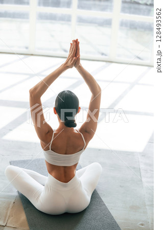 Lotus pose. Young woman with slim body type is in fitness clothes in the studio 128493562