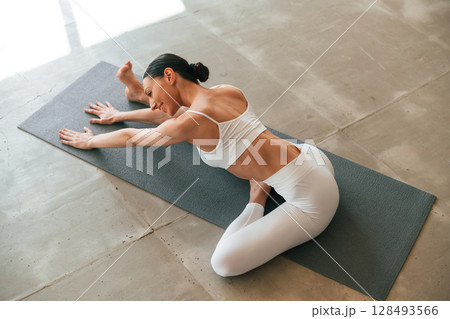 Warm up exercises. Young woman with slim body type is in fitness clothes in the studio 128493566