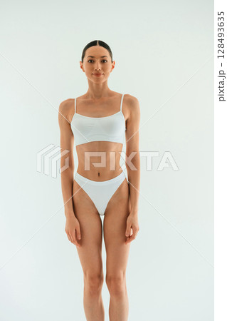 Front view. Young woman with slim body type is in fitness clothes in the studio 128493635