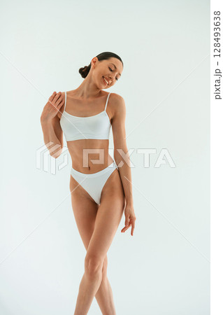 Front view. Young woman with slim body type is in fitness clothes in the studio 128493638