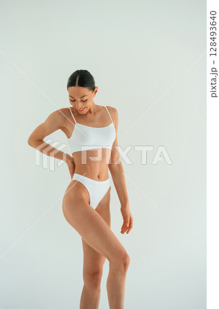 Clean skin, standing. Young woman with slim body type is in fitness clothes in the studio Clean skin, standing. Young woman with slim body type is in fitness clothes in the studio 128493640