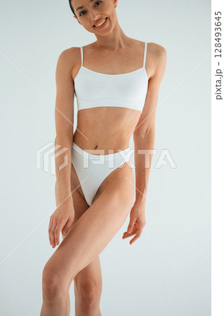 Clean skin, standing. Young woman with slim body type is in fitness clothes in the studio 128493645