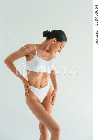 Showing the slim body type. Young woman is in fitness clothes in the studio 128493664