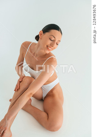 Sitting, enjoying the break time. Young woman with slim body type is in fitness clothes in the studio Sitting, enjoying the break time. Young woman with slim body type is in fitness clothes in the studio 128493676