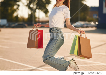 Close up view. Beautiful woman in casual clothes is holding shopping bags, outdoors Close up view. Beautiful woman in casual clothes is holding shopping bags, outdoors 128494268