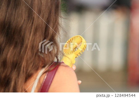 ハンディファンを持って歩く女性 ハンディファンを持って歩く女性 128494544