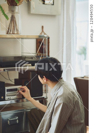 部屋でオーディをいじる男性 128494550