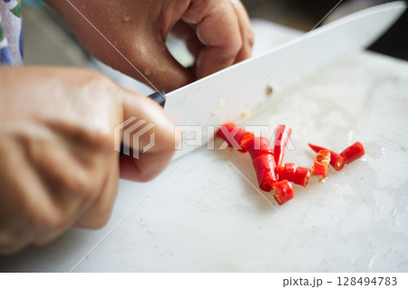 slicing Chilli pepper with Knife on chopping board slicing Chilli pepper with Knife on chopping board 128494783