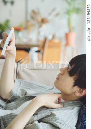 リビングでスマホを見る男性 128494870