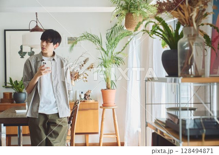 リビングでスマホを見る男性 128494871