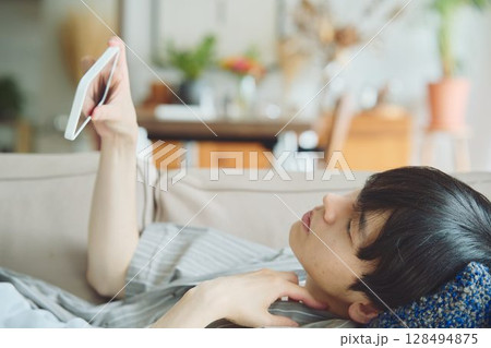 リビングでスマホを見る男性 128494875