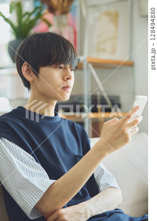 リビングでスマホを見る男性 128494880