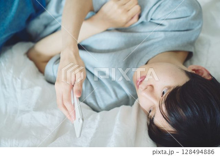 ベッドでスマホを見る若い男性 ベッドでスマホを見る若い男性 128494886