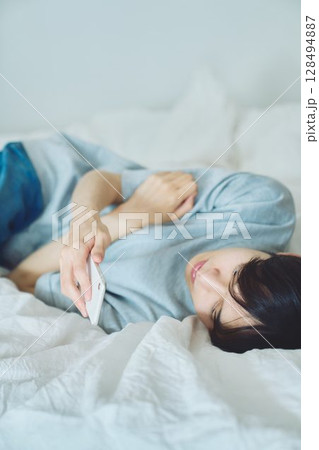 ベッドでスマホを見る若い男性 ベッドでスマホを見る若い男性 128494887