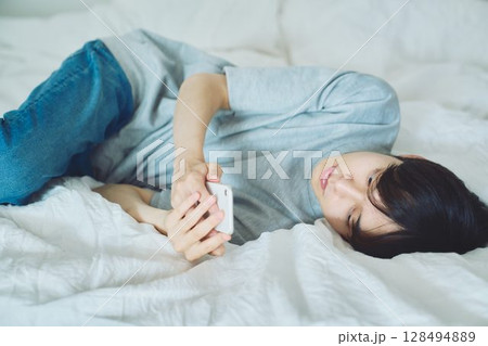 ベッドでスマホを見る若い男性 128494889