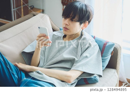 リビングでスマホを見る男性 128494895