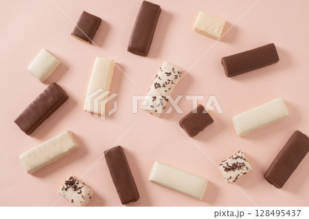 Different whey protein bars with various coatings and sprinkles scoop of protein powder on pink background. Healthy fitness snacks. View from above. Food abstract pattern. 128495437