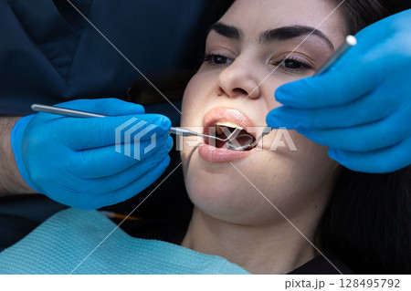 Dental Examination in Progress: Dentist Checking Patient's Oral Health Using Tools and Techniques for a Thorough Check-Up Experience 128495792