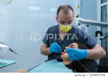 Professional Dentist Providing Dental Care During Oral Procedure with Patient in Dental Chair at Modern Clinic, Emphasizing Importance of Hygiene and Comfort in Dentistry Environment 128495798
