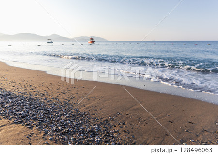 A picturesque beach setting with smooth sands, scattered pebbles 128496063